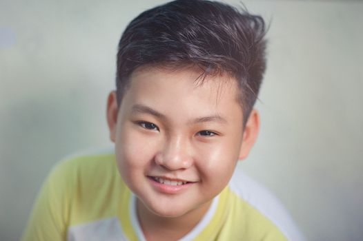 A happy young boy smiling indoors, showcasing joy and innocence.